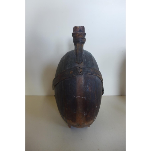 1242 - A carved moon shaped wooden flask, 26cm tall, with remains of leather strapping, general wear and cr... 