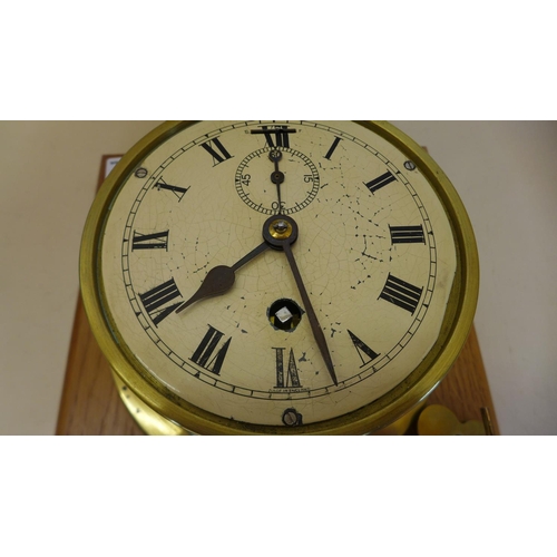 68 - A brass Ships clock mounted on oak board with key - 26cm x 23cm - running, some wear to dial