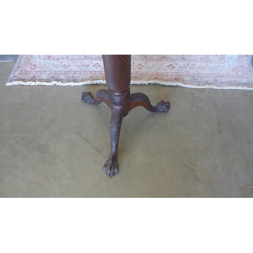 62 - A mahogany torchere on a carved tripod base with ball and claw feet. 134 cm tall