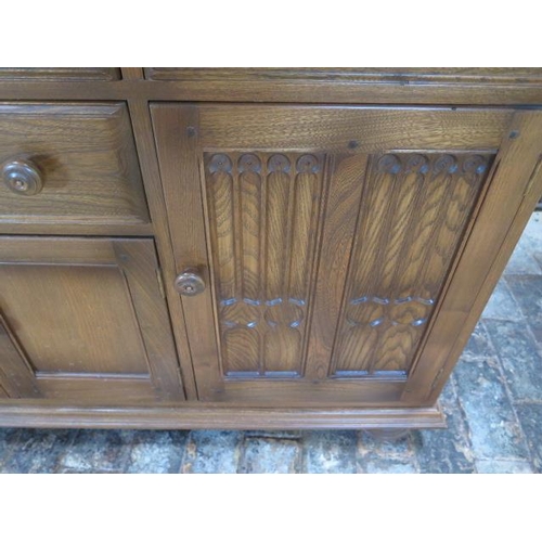 24 - An Ercol elm gothic style Canterbury dresser base with 4 drawers and 4 cupboard doors, 90cm tall x 1... 