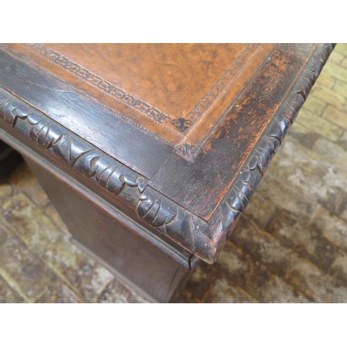 77 - An oak kneehole writing desk with tooled leather top and ornate 'Green Man' carved drawers, 107cm wi... 