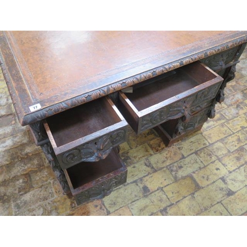 77 - An oak kneehole writing desk with tooled leather top and ornate 'Green Man' carved drawers, 107cm wi... 