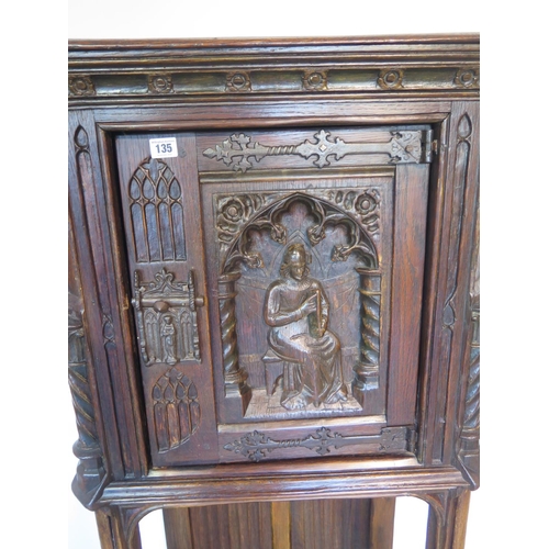135 - A 19th century Gothic oak tall cupboard with carved figural door over a single under tier, 137cm tal... 