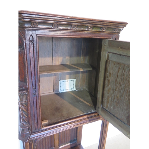 135 - A 19th century Gothic oak tall cupboard with carved figural door over a single under tier, 137cm tal... 