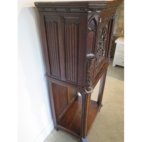 135 - A 19th century Gothic oak tall cupboard with carved figural door over a single under tier, 137cm tal... 