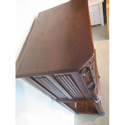 135 - A 19th century Gothic oak tall cupboard with carved figural door over a single under tier, 137cm tal... 