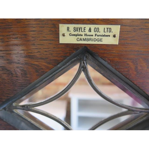 89 - A carved oak 1930s cabinet with a leaded glazed door above a cupboard door on turned feet with a Rob... 