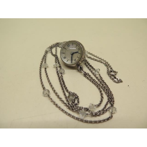 962 - A white metal pendant watch and chain, the dial detailed E GUBELIN, moisture to interior glass