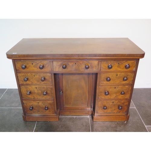 100 - A Victorian mahogany nine drawer desk / dressing chest with a central cupboard, 82cm tall x 127cm x ... 