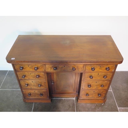 100 - A Victorian mahogany nine drawer desk / dressing chest with a central cupboard, 82cm tall x 127cm x ... 