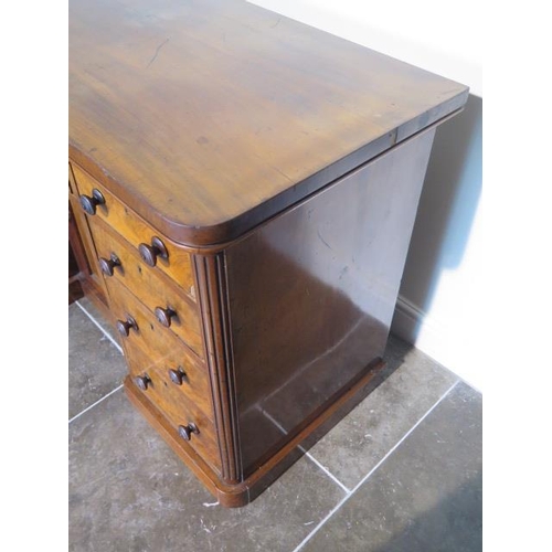 100 - A Victorian mahogany nine drawer desk / dressing chest with a central cupboard, 82cm tall x 127cm x ... 