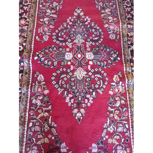 270 - A hand knotted woollen rug with a red field, 280cm x 140cm, generally good condition