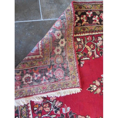 270 - A hand knotted woollen rug with a red field, 280cm x 140cm, generally good condition