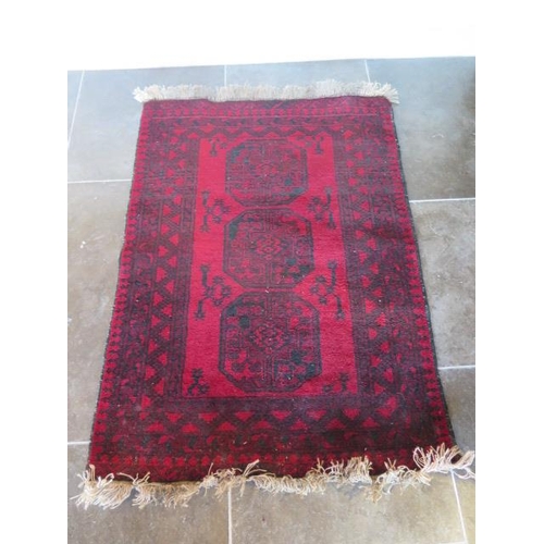 271 - A small hand knotted woollen rug with a red field, 150cm x 100cm, generally good condition