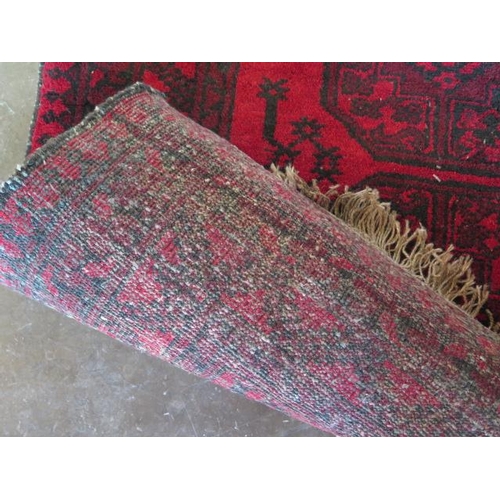 271 - A small hand knotted woollen rug with a red field, 150cm x 100cm, generally good condition