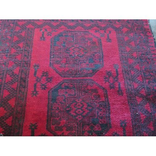 271 - A small hand knotted woollen rug with a red field, 150cm x 100cm, generally good condition