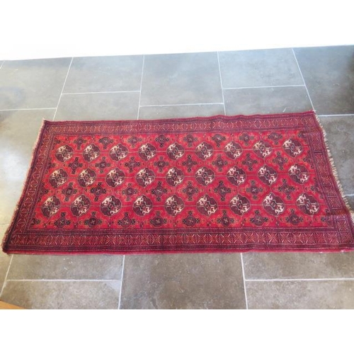 272 - A small hand knotted woollen rug with a red field, 190cm x 96cm, generally good condition