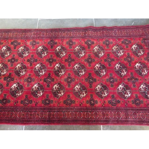 272 - A small hand knotted woollen rug with a red field, 190cm x 96cm, generally good condition