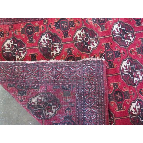 272 - A small hand knotted woollen rug with a red field, 190cm x 96cm, generally good condition