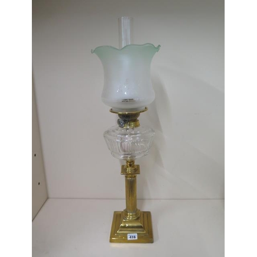 416 - A brass oil lamp with clear glass reservoir and green tinted shade, 67cm tall, in good condition and... 