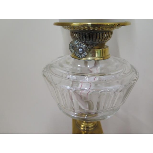 416 - A brass oil lamp with clear glass reservoir and green tinted shade, 67cm tall, in good condition and... 