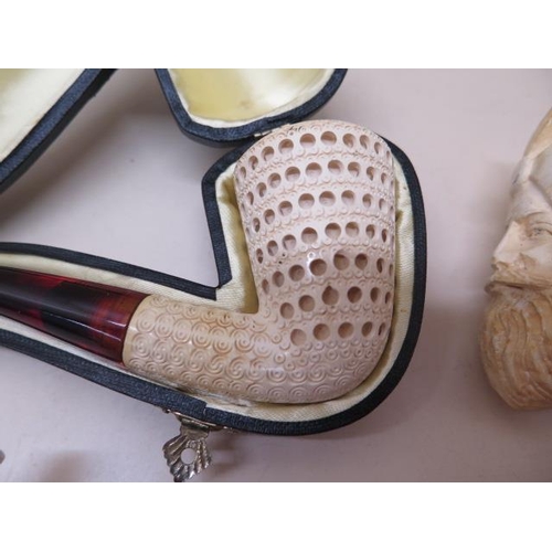 439 - A collection of four pipes to include two Meerschaum Turkish head pipes, a cased pierced reticulated... 