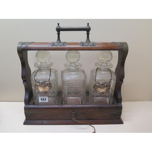 443 - An oak three bottle tantalus with two silver spirit labels, 36cm tall x 37cm wide, small chips to on... 