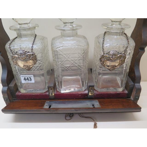 443 - An oak three bottle tantalus with two silver spirit labels, 36cm tall x 37cm wide, small chips to on... 