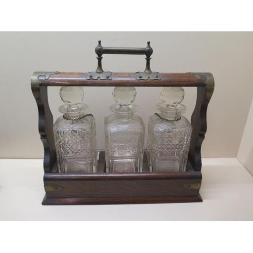 443 - An oak three bottle tantalus with two silver spirit labels, 36cm tall x 37cm wide, small chips to on... 