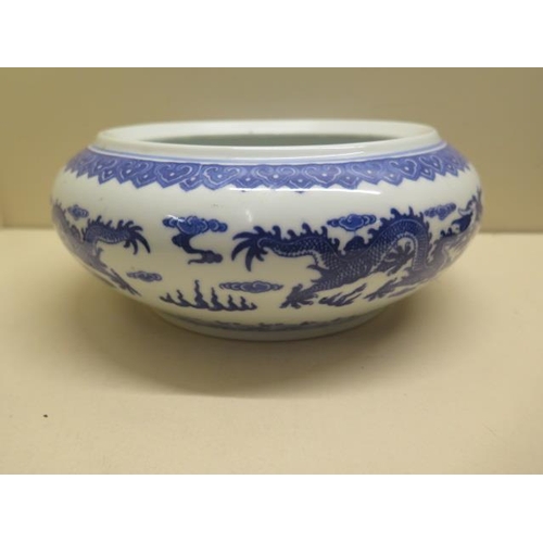 444 - An oriental blue and white dragon bowl on a hardwood stand, total 14cm tall x 22cm diameter, no obvi... 