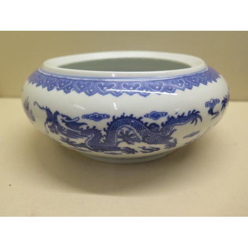 444 - An oriental blue and white dragon bowl on a hardwood stand, total 14cm tall x 22cm diameter, no obvi... 