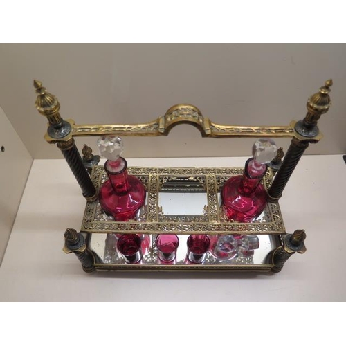 488 - An ornate gilt metal 3 bottle cranberry glass liquor stand with 2 bottles, a stopper and 3 glasses. ... 