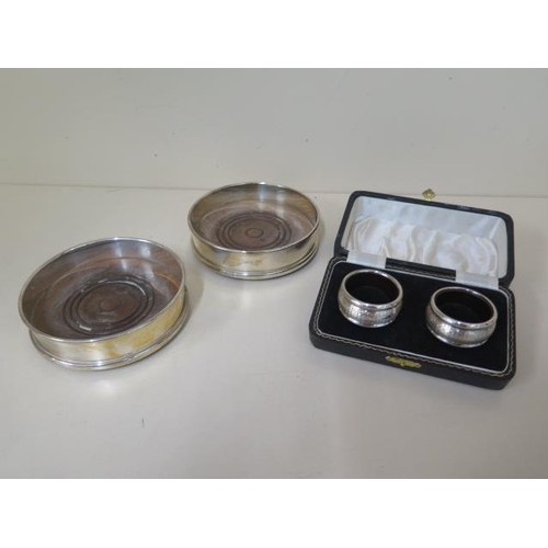 602 - A pair of lined silver napkin rings boxed and a pair of silver rimmed wine coasters, no engraving, s... 