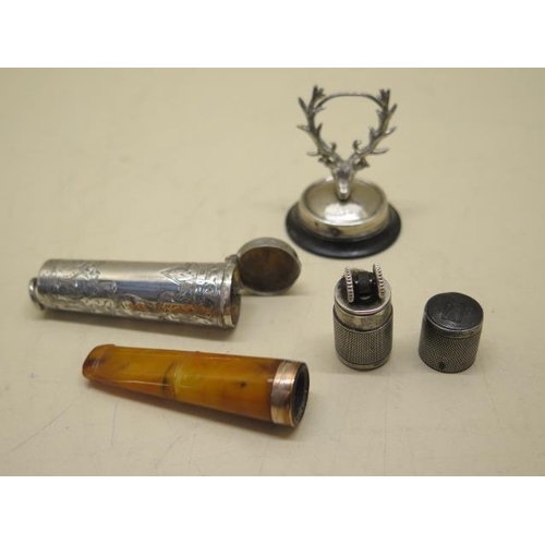 611 - A silver petrol lighter, a silver stags head menu holder and a silver cheroot holder case, all gener... 