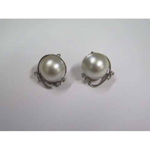 711 - A pair of 18ct white gold diamond and pearl earrings, 22mm wide, approx 15.8 grams, in good conditio... 