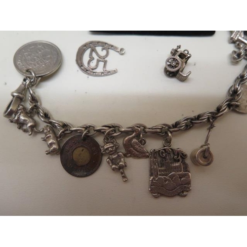 719 - A silver charm bracelet with spare charms and a non silver coin, approx 2.2 troy oz, bracelet is 20c... 