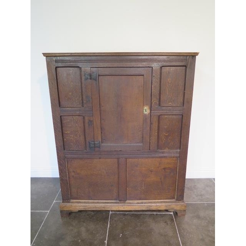 73 - An 18th century oak panelled cupboard with a single central door, 148cm tall x 117cm x 50cm, some la... 