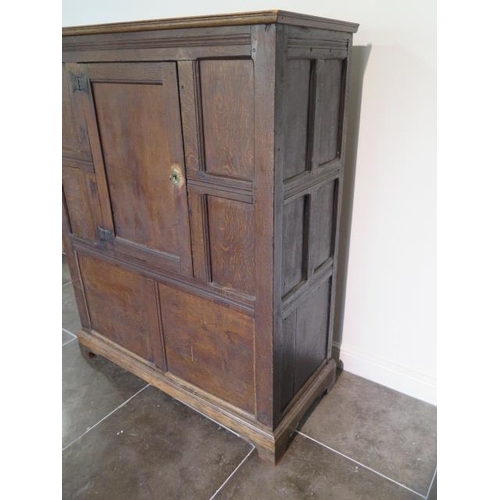 73 - An 18th century oak panelled cupboard with a single central door, 148cm tall x 117cm x 50cm, some la... 