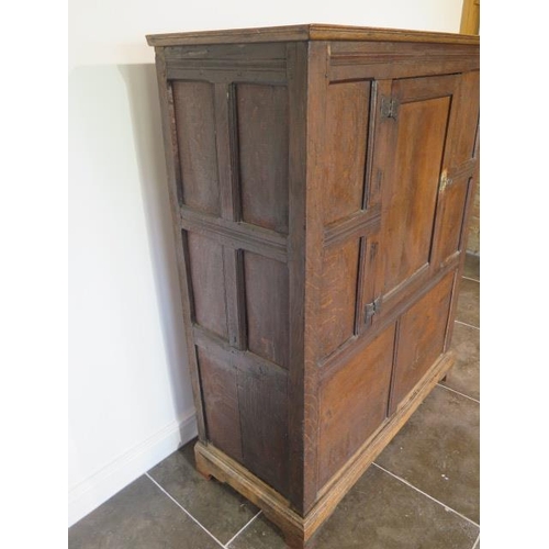 73 - An 18th century oak panelled cupboard with a single central door, 148cm tall x 117cm x 50cm, some la... 