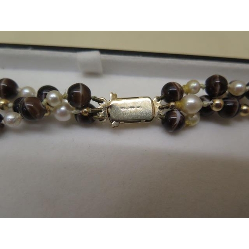 767 - A tiger eye, pearl and gold bead three strand necklace with a 9ct gold clasp, 38cm long, in good con... 