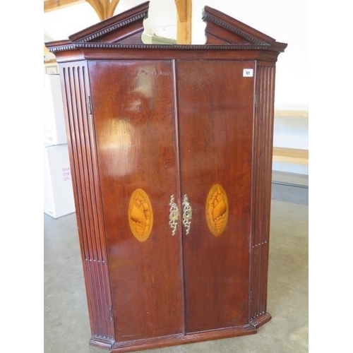 81 - A 19th century mahogany breakfront corner cupboard with two shell inlaid doors enclosing a painted i... 