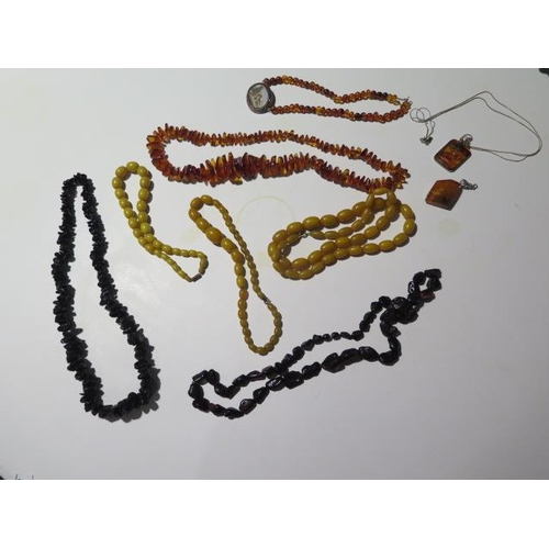 947 - A collection of seven burnt amber and amber type necklaces, one with a micro mosaic pendant and two ... 