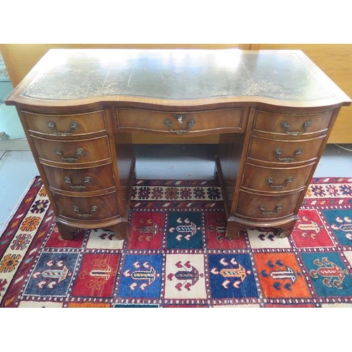 56 - A mahogany serpentine fronted nine drawer kneehole desk with a leather inset top, 75cm tall x 116cm ... 