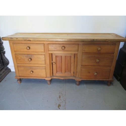 67 - A Victorian stripped pine dresser with 7 drawers and a central door, 82cm tall x 172cm x 46cm