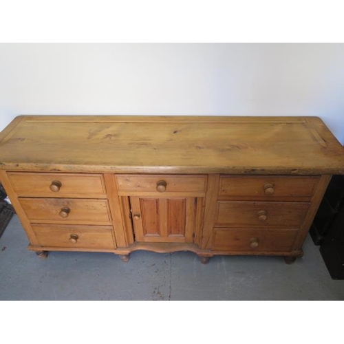 67 - A Victorian stripped pine dresser with 7 drawers and a central door, 82cm tall x 172cm x 46cm