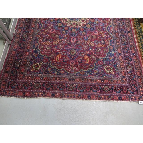 204 - A vintage woollen rug with a red field and a central medallion, 197cm x 129cm, wear mainly to fringe... 