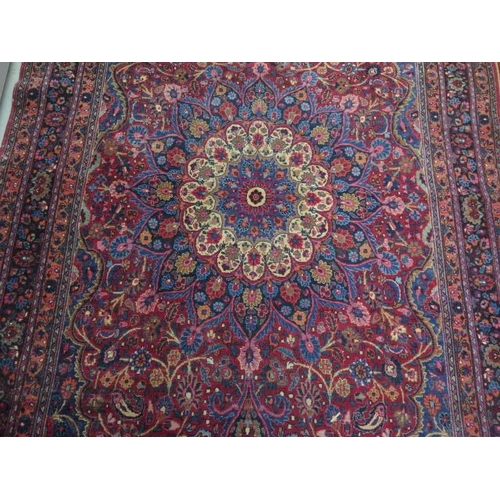 204 - A vintage woollen rug with a red field and a central medallion, 197cm x 129cm, wear mainly to fringe... 