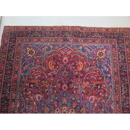 204 - A vintage woollen rug with a red field and a central medallion, 197cm x 129cm, wear mainly to fringe... 