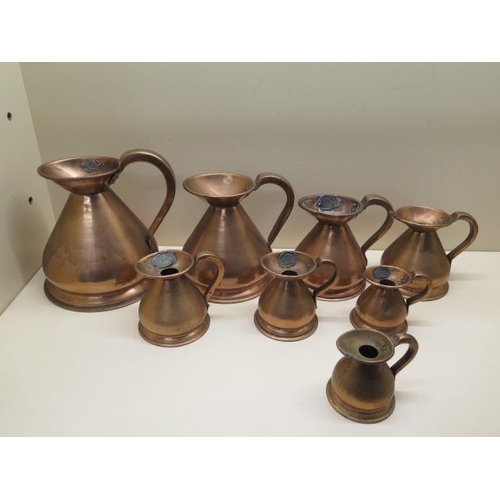 342 - A set of 8 copper measuring jugs ranging from 1/8 Gill to a Quart, 17cm tall