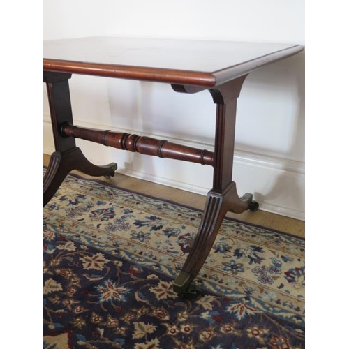 94 - A mahogany side table in the Regency style on twin supports with brass caps and casters, 46cm tall x... 